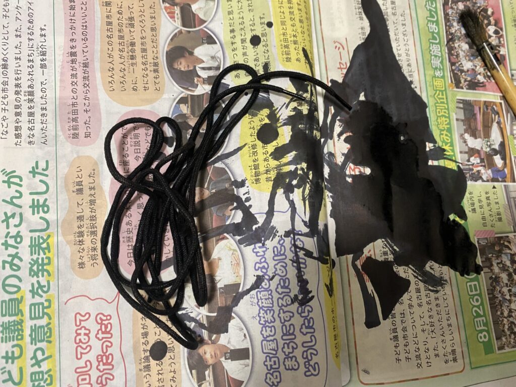 黒に染めた靴ひもと、染料が付いた新聞紙と刷毛